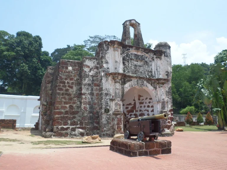 The ancient stone gate of A Famosa fortress in Malacca, with a historical cannon positioned in front of it.