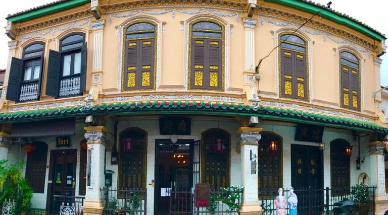 The ornate facade of the Baba Nyonya Heritage Museum, a traditional Peranakan shophouse with intricate carvings and traditional Chinese architecture in Malacca.