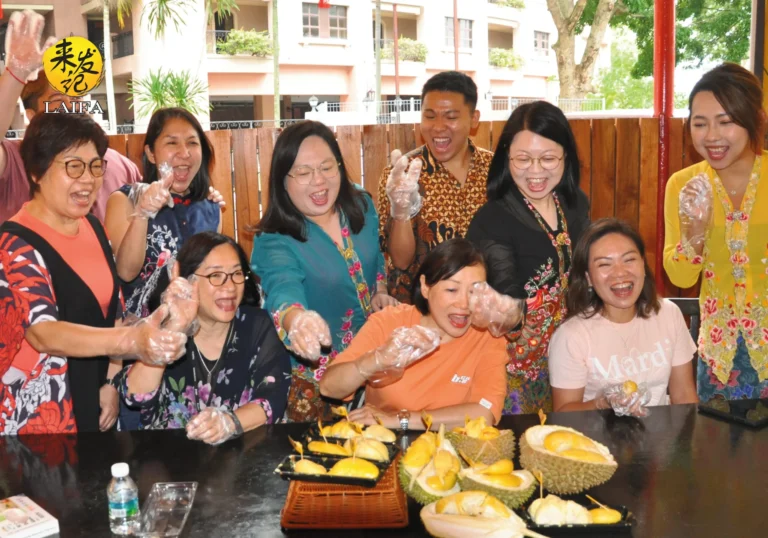 A joyful group of people excitedly eating fresh durian fruit at a table.